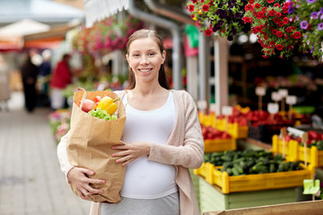 pregnant woman with bag of food at street market