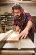 © mavoimages - Carpenter wearing protective gear cutting a plank of wood