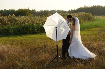 Just Married Couple with Photographer's Umbrella in a field