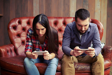 Canvas Print - woman and man sitting on the sofa with smartphone