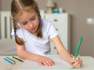 Little girl drawing with pencil at home.