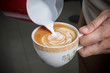 Latte art, barista pouring milk to make coffee latte art.