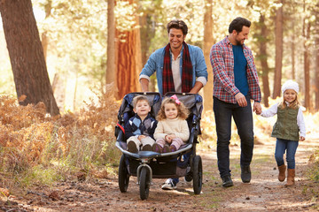 Wall Mural - Gay Male Couple Pushing Children In Buggy Through Woods