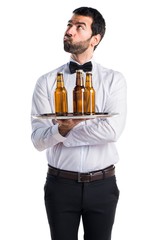 Wall Mural - Waiter with beer bottles on the tray having doubts