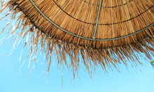 Straw Beach Umbrella On Blue Sky Background
