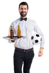 Wall Mural - Waiter with beer bottles on the tray holding a soccer ball