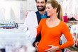 Schwangere Frau und Mann kaufen Strampler im Baby Laden