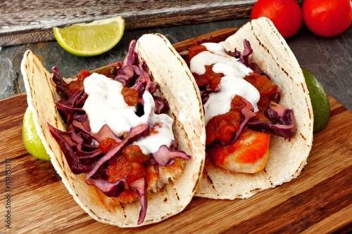 Two spicy fish tacos with red cabbage lime slaw, salsa and sour cream on wooden Plakát