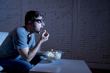  television addict man on sofa watching TV and eating popcorn in funny nerd geek glasses