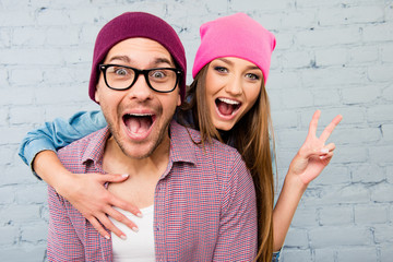 Wall Mural - Portrait of two happy  lovers in caps huging and screaming