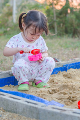 Wall Mural - Little asian girl playing in sandbox