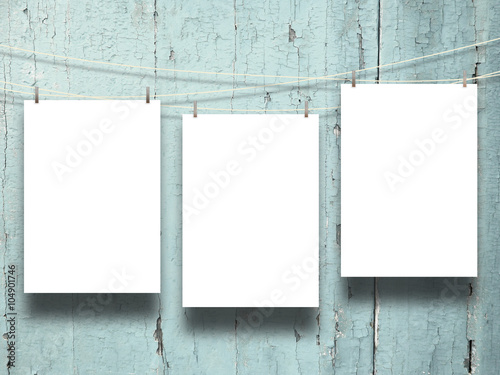 Fotografie, Obraz Close-up of three hanged paper sheets with pegs on weathered aqua wooden boards