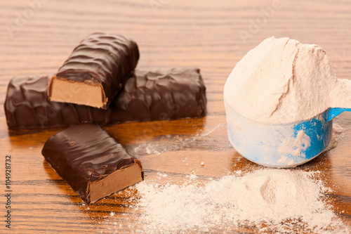 Fotografia Whey protein powder in measuring scoop and chocolate protein bar