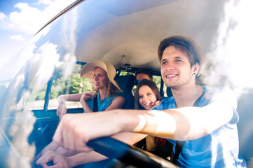 Wall Mural - Hipster boy driving an old campervan with teenagers, roadtrip