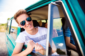 Wall Mural - Teenage boys and girls inside an old campervan, roadtrip