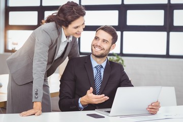 Young business people discussing over laptop