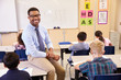 © Monkey Business - Smiling elementary school teacher sitting on a pupil’s desk