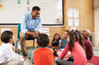 © Monkey Business - Elementary school kids sitting around teacher in a classroom