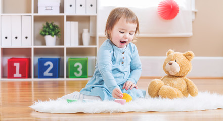 Wall Mural - Toddler girl have tea with her teddy bear