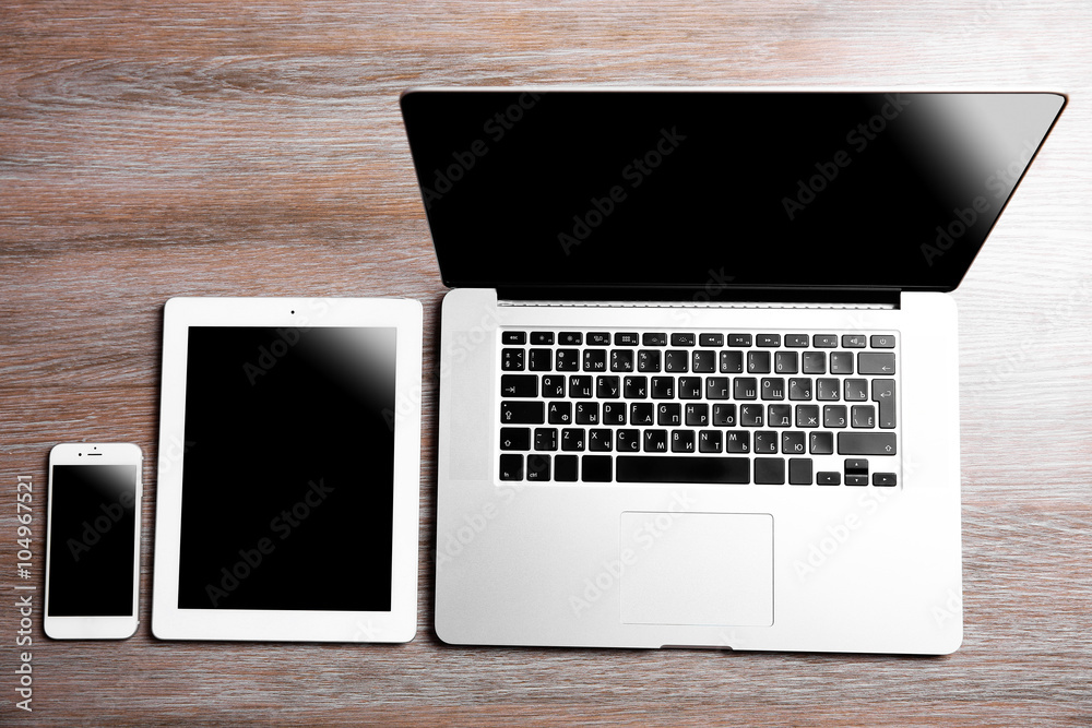 Modern laptop, smart phone and tablet on a wooden table