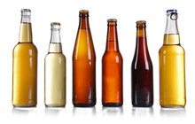 Glass Bottles Of Different Beer On Light Grey Background