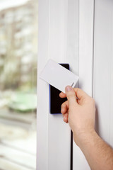 Security alarm keypad with male hand and card, closeup