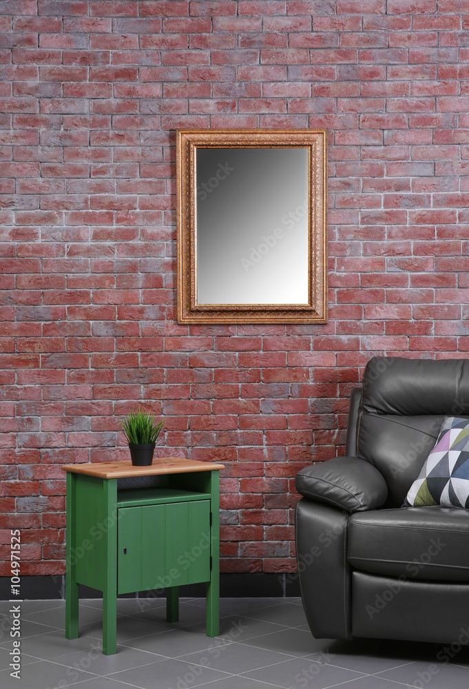 Brown leather armchair and green small table against brick wall background