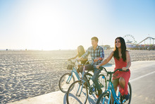 Three Friends Riding Bikes Together On Santa Monica Beach With Copy Space