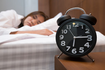 Asian woman sleeping in bed and alarm clock