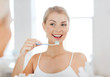 © Syda Productions - woman with toothbrush cleaning teeth at bathroom