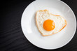 Fried egg in form of heart on a black background
