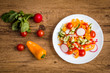 Salad with cherry tomatoes, sweet peppers, cucumbers and radishes on a wooden background