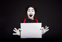 Smiling Female Mime Holding White Sheet Of Paper/ Crazy Smiling Girl Mime Holding White Sheet Of Paper On Black Background