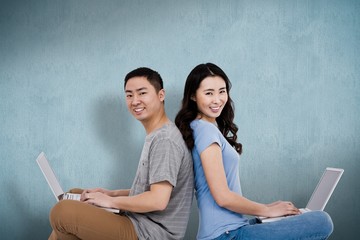 Composite image of portrait of young happy couple using laptop