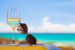 glass of chilled white wine and sunglasses on table near the beach
