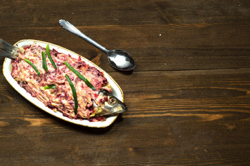  salad herring under a fur coat on a wooden table in the backgro