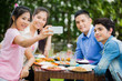 © torwaiphoto - Asians are eating Thailand food garden on the grounds. While eating a woman on the phone taking pictures with friends in a selfie