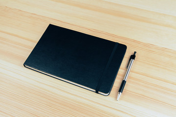 Poster - Blank cover of notebook with pen on wooden table, mock up