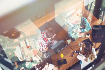 Group of young people sitting at a cafe, with mobiles and tablets, top view