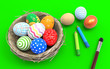 Colorful Easter eggs in a nest from branches on a green background