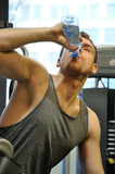 Mężczyzna na siłowni pijący wodę.