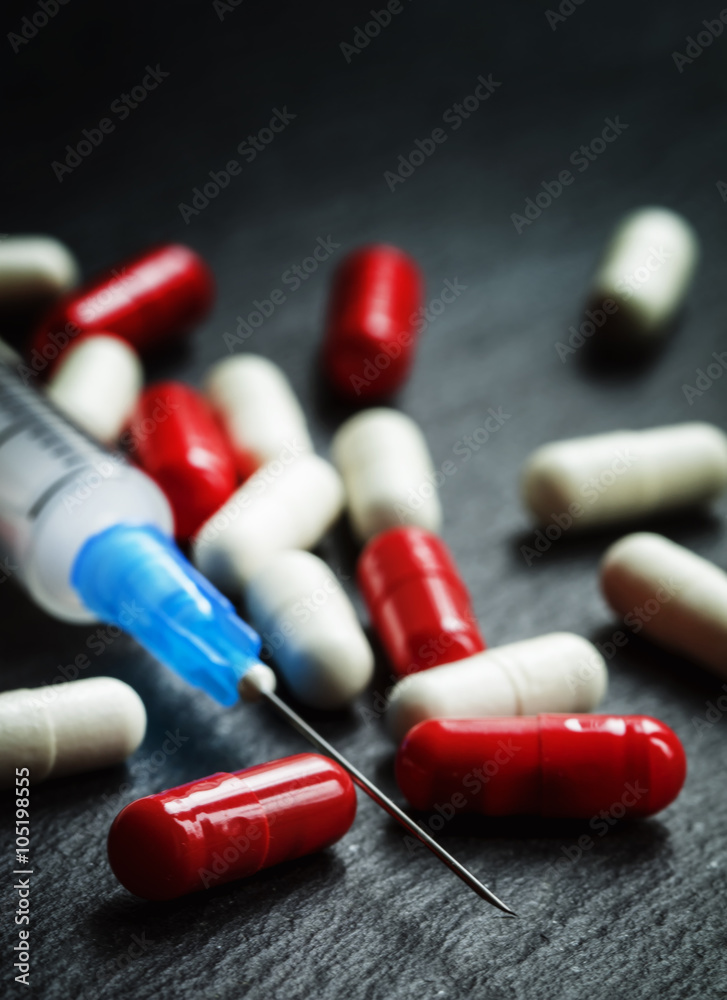 Red and white tablets in capsules, syringe for injection, dark b Stock ...