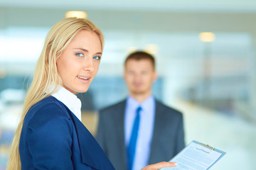 Businesswoman standing in office , holding documents in hand