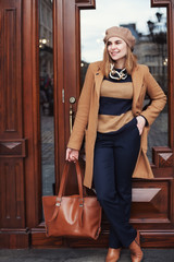 Street photo of young beautiful happy smiling lady wearing stylish classic clothes. Model looking aside. Full body portrait. Female fashion concept. City lifestyle. 