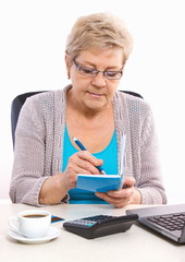 Elderly senior woman writing in notebook or calendar