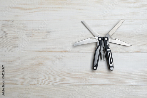 Multi tool with black handles on a white wooden background Tablou Canvas