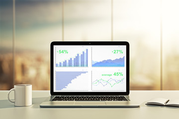 Poster - Laptop with financial statistics on a desktop at sunset
