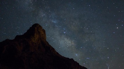 Wall Mural - Milky Way stars move behind a desert mountain - time lapse