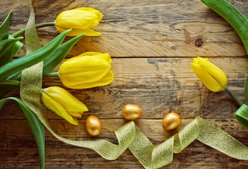 Wall Mural - Easter background with yellow tulips, golden eggs