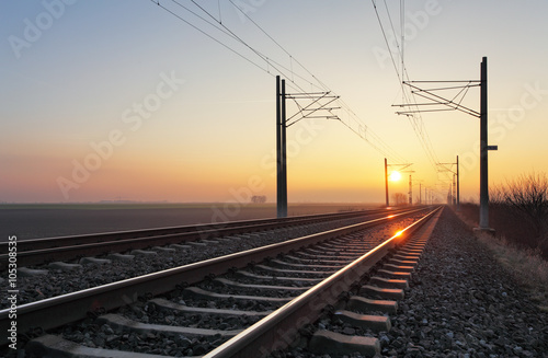 Fotomural Railroad - Railway at sunset with sun